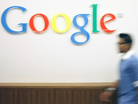 Man walking past Google sign