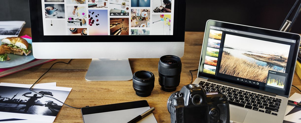 Two computer screens with lots of pictures and camera on a desk