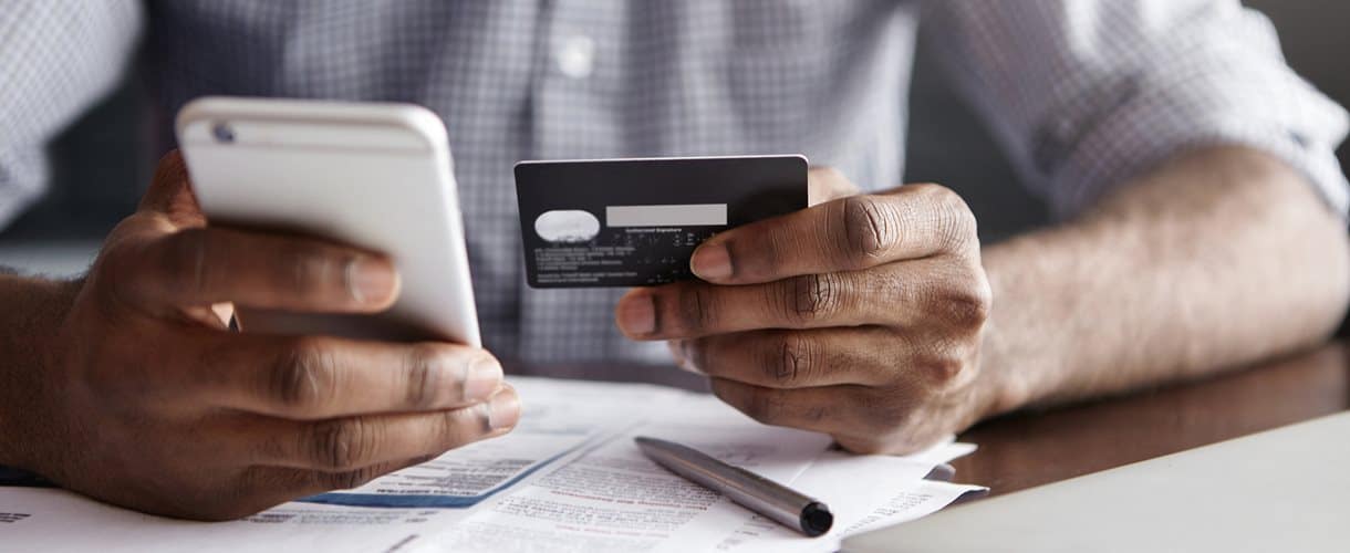 Man holding his mobile phone and debit or credit card