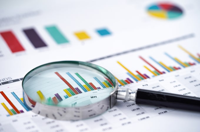 Magnifying Glass On Charts Graphs Spreadsheet Paper.