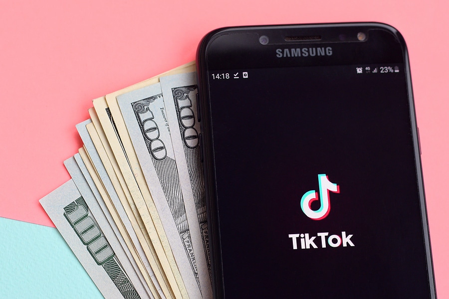 Phone with Tiktok logo lying on stack of money