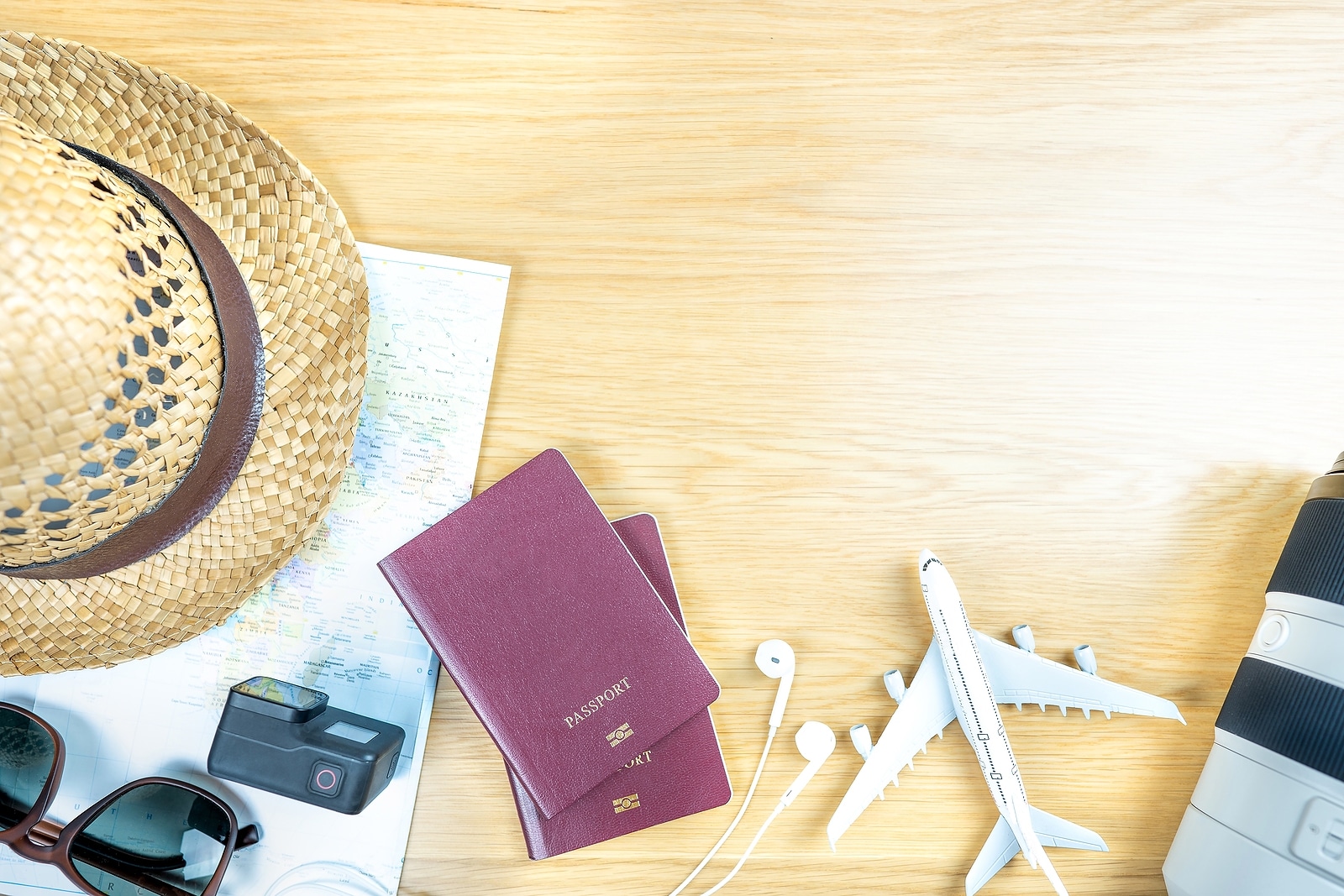 Passport sunhat and map laid out on table for summer holiday