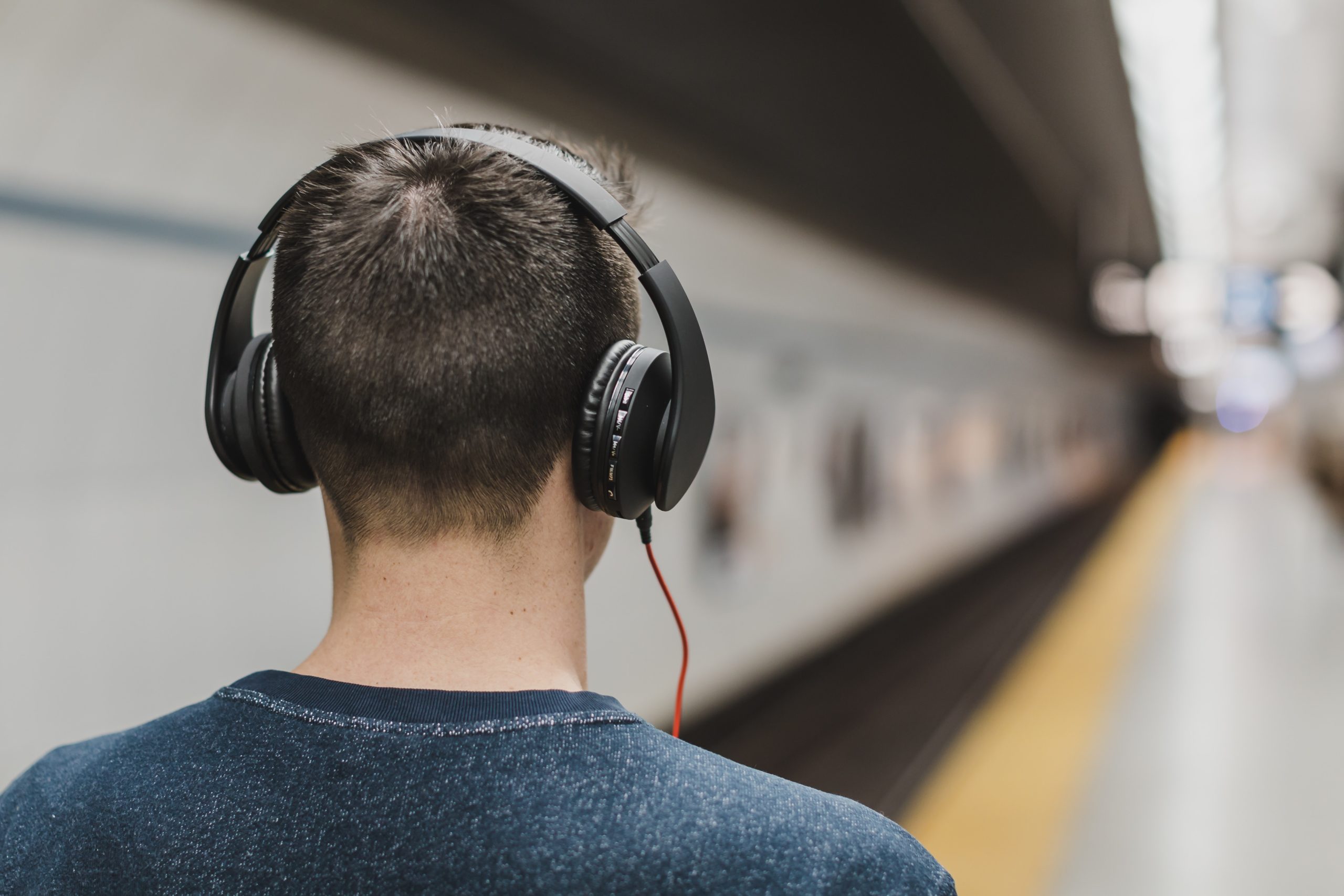 Man at tube station listening to music with headphones