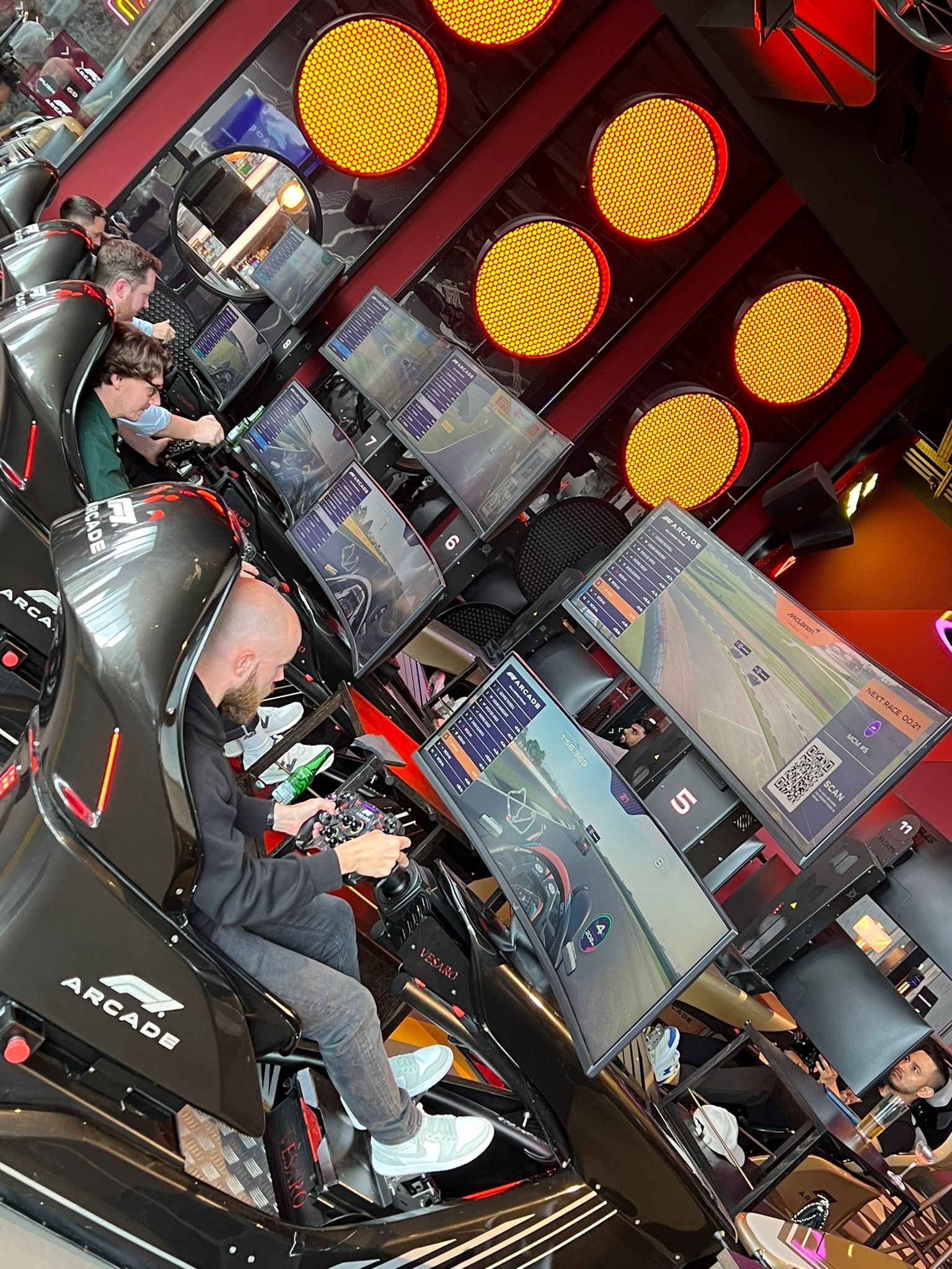 People racing cars at an arcade. 