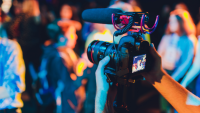 A professional camera filming a lively event 