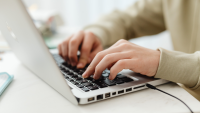 hands typing on a silver macbook laptop